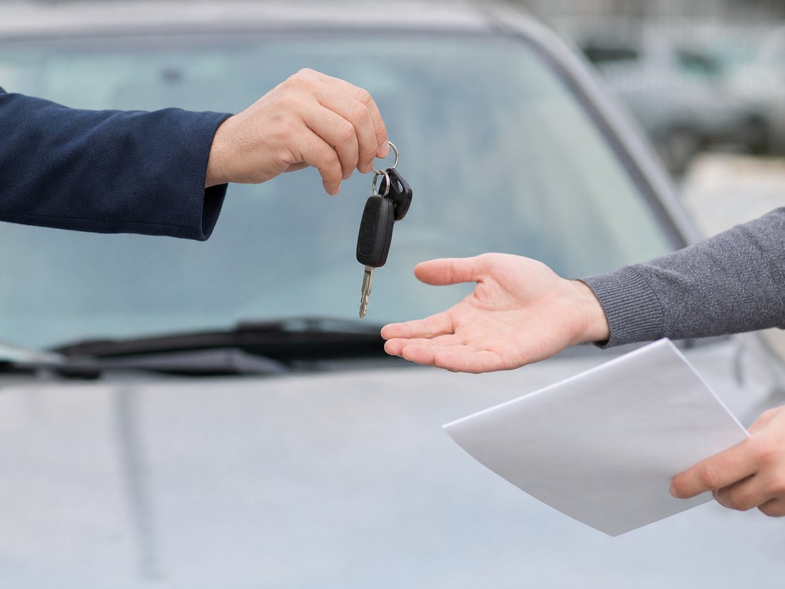 Keys and a document changing hands over a car bonnet